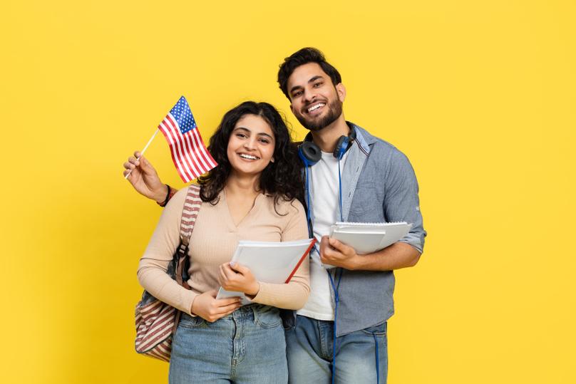 Cheerful Students Holding an American Flag and Books