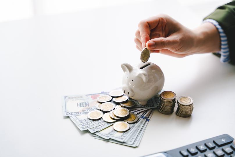 young woman putting coins in a piggy bank to save money