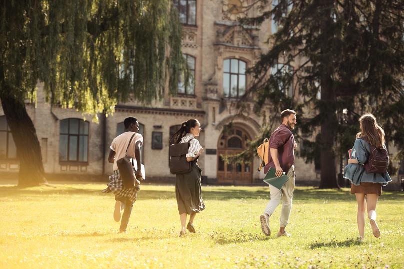 back view of happy multicultural students running to university