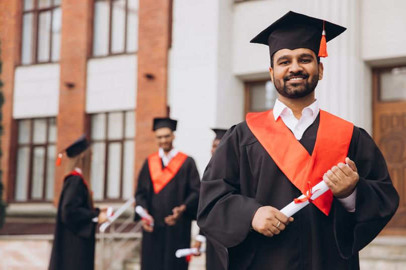 Happy Male Indian Graduates Posing Proudly in Cap and Gown at University Graduation Ceremony