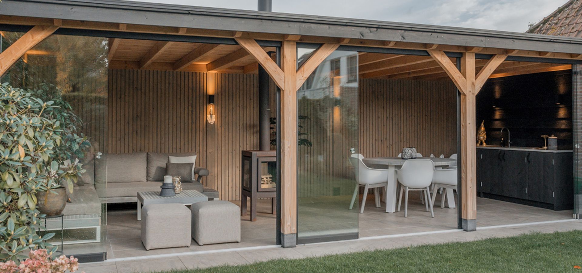 Houten buitenverblijf voorzien van loungemeubels en een buitenkeuken