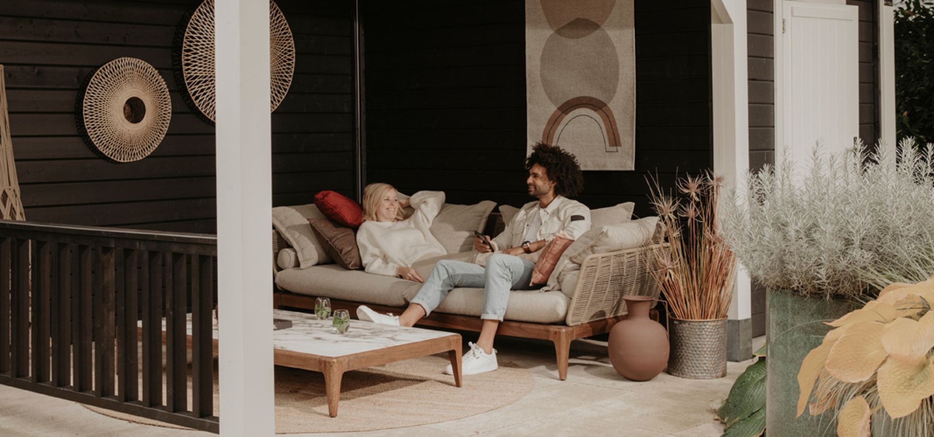 Man en vrouw zitten samen op een loungebank in hun buitenverblijf