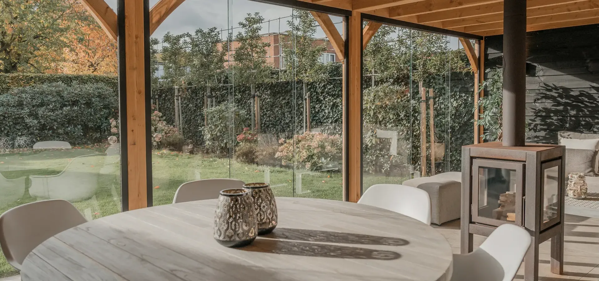 binnezijde van een houtenbuitenverblijf ingericht met een eettafel en zithoek en voorzien van glazen schuifwanden