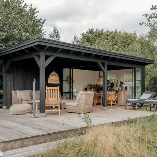 Houten buitenverblijf ingericht met loungebank en eettafel