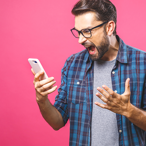 A stock photo of a man yelling at a cell phone in frustration against a pink gradient background.