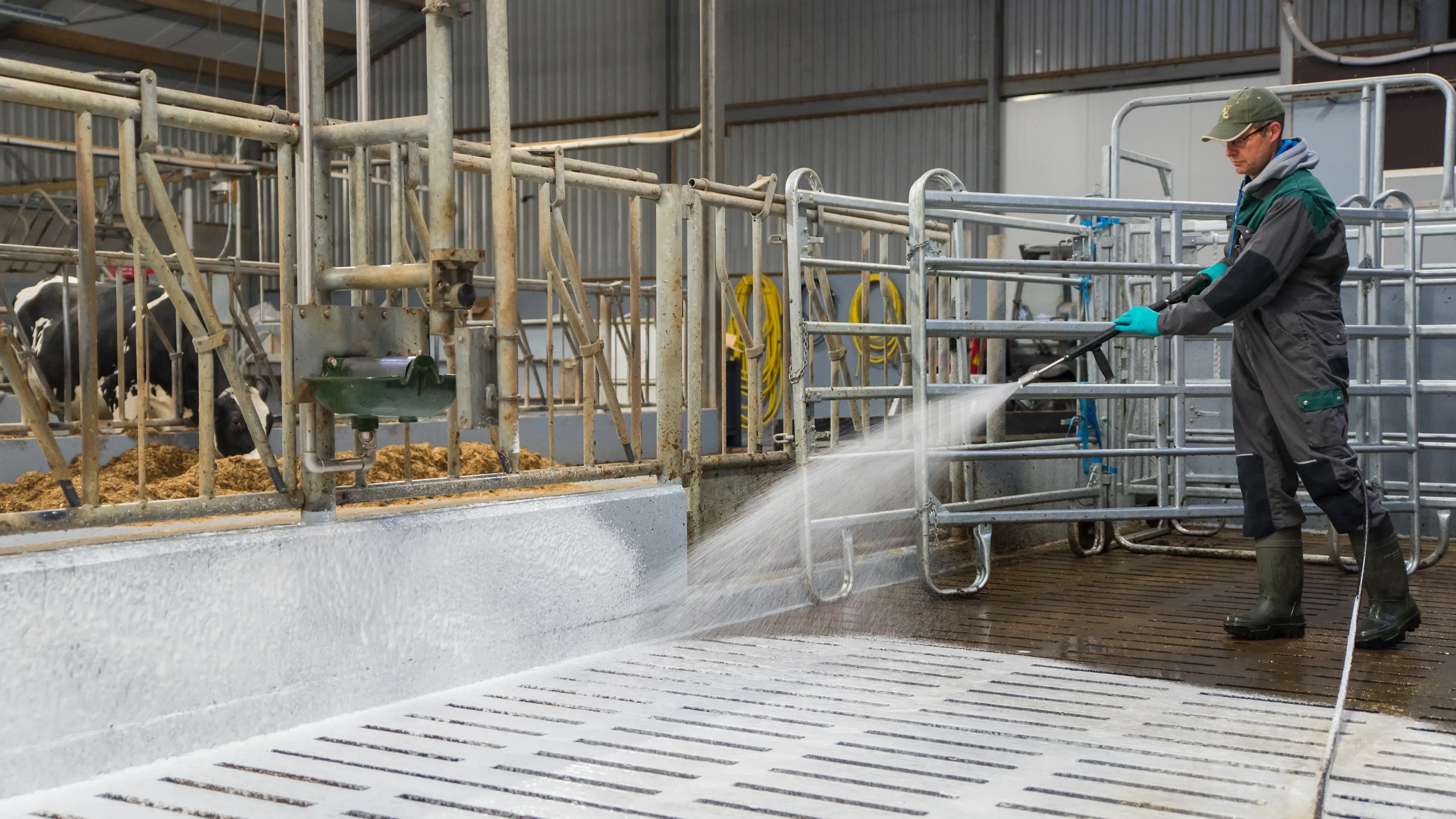 Man in green overall cleaning with high pressure