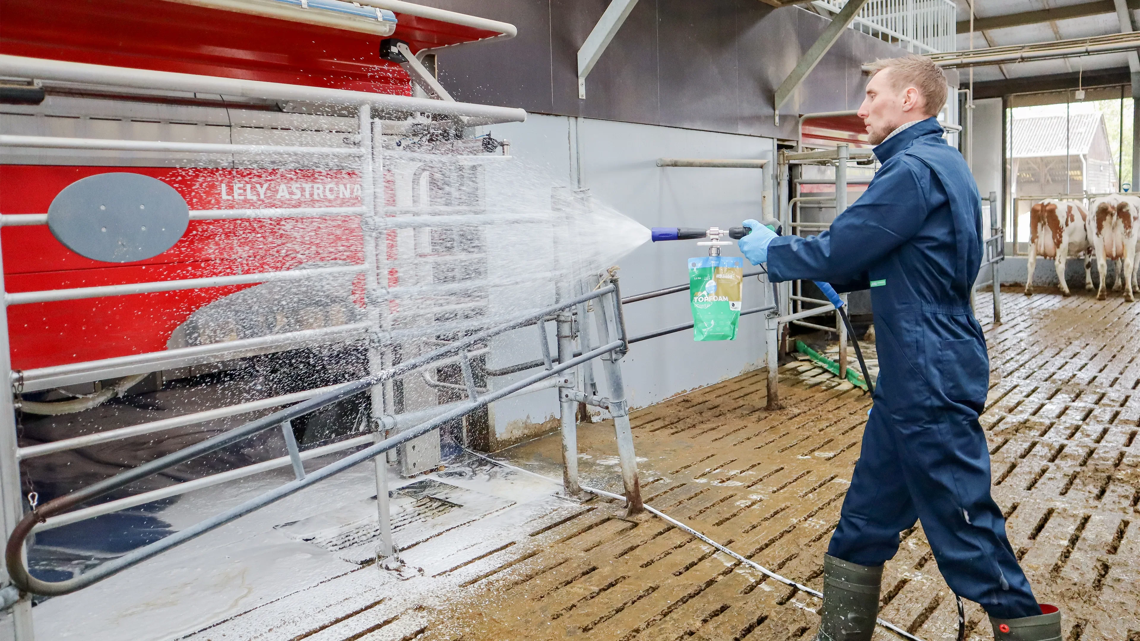 Man in blue overall cleaning a stall with Hybag using high pressure