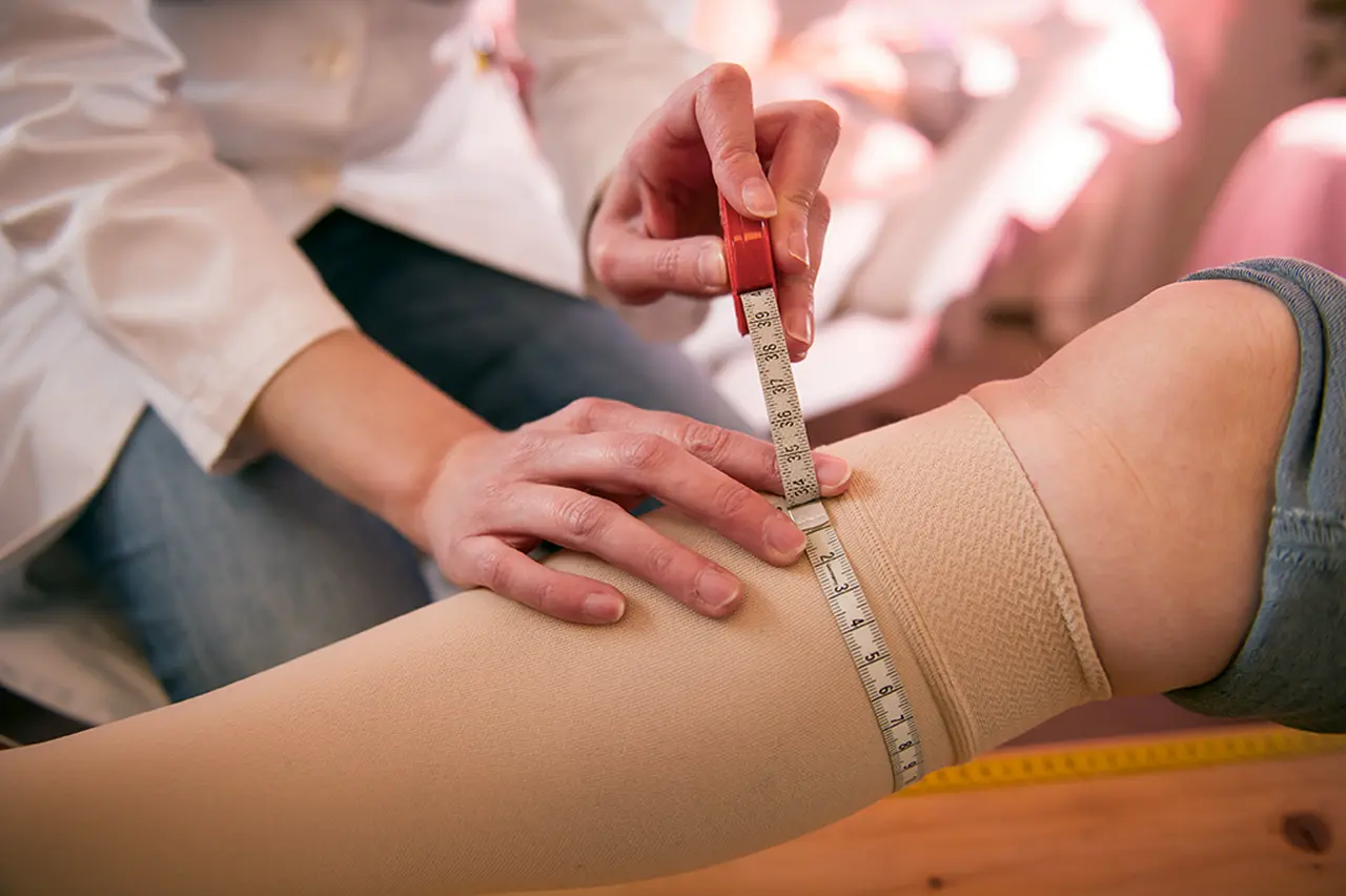 Kompressionsstrümpfe Knie oder Oberschenkel, Wade von Frau wird abgemessen, Hilfe bei Krampfadern, Ödeme