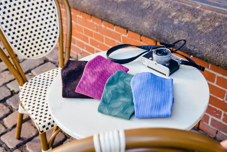 Kompressionsstrümpfe in verschiedenen Farben liegen auf einem Café-Tisch mit einer Kamera