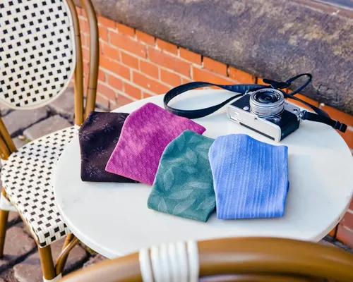 Kompressionsstrümpfe in verschiedenen Farben liegen auf einem Café-Tisch mit einer Kamera