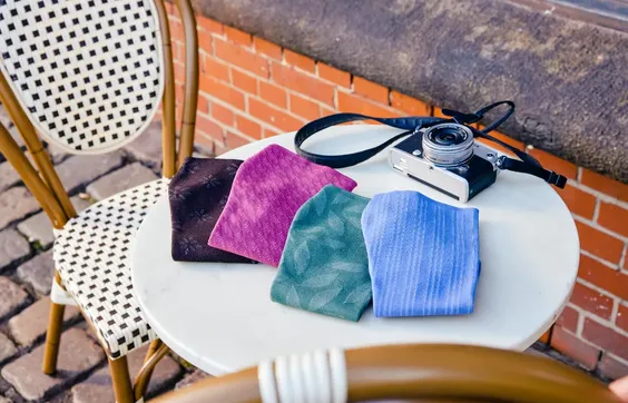 Kompressionsstrümpfe in verschiedenen Farben liegen auf einem Café-Tisch mit einer Kamera