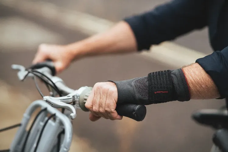 Handgelenk mit Bandage eines älteren Mannes, der ein Fahrradlenkrad festhält