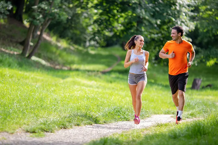 Knieschmerzen beim Joggen, joggendes Paar auf Wiese, Knie stabilisieren durch Übungen