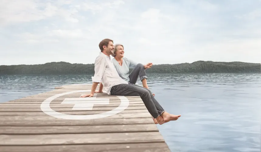 Mann und Frau mit Knick-Senk-Spreizfuß sitzen am Rand von einem Pier an einem See