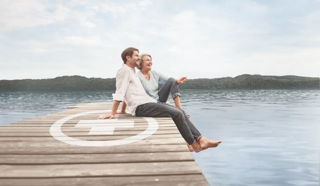 Mann und Frau mit Knick-Senk-Spreizfuß sitzen am Rand von einem Pier an einem See
