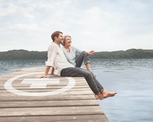 Mann und Frau mit Knick-Senk-Spreizfuß sitzen am Rand von einem Pier an einem See