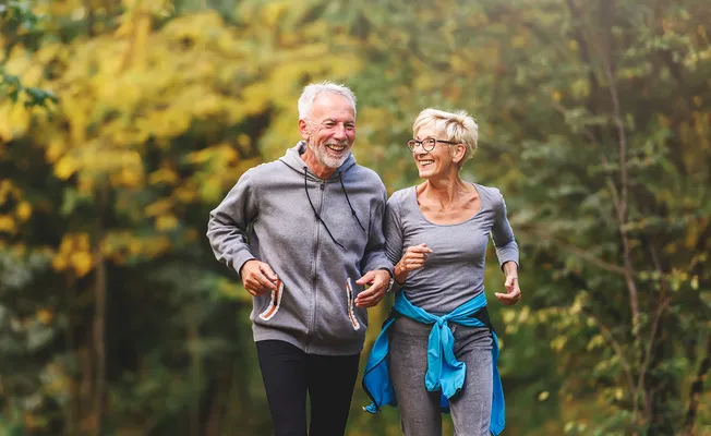 Pärchen joggend im Wald mit TENA Essity Inkontinenzeinlage