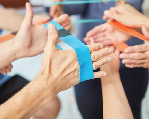 mehrere Personen machen Übung für Hände, wegen Schmerzen im Handgelenk, ziehen Sportband mit Händen auseinander