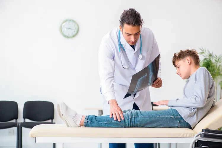 Parese, betroffener Jugendlicher bei Untersuchung mit Arzt, Bewegungseinschränkung, unvollständige Lähmung der Skelettmuskulatur