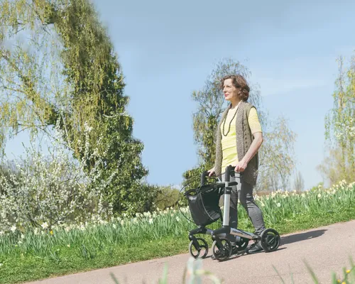 Frau mit Parkinson schiebt Rollator einen Abhang im Park herunter