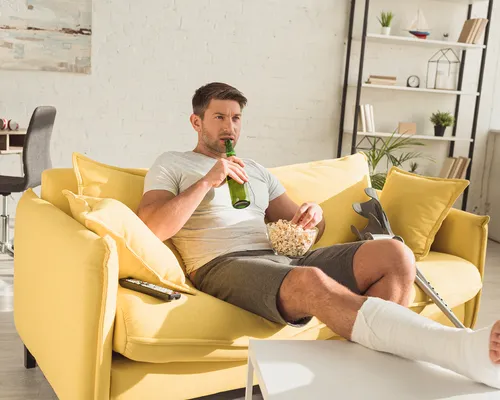 Gips oder Orthese, Mann zuhause mit Gips und Krücken,  Knochenbruch