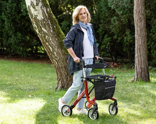 Frau mit Parkinson mit Rollator auf grüner Wiese, im Hintergrund Bäume, Charcot-Marie-Tooth-Syndrom
