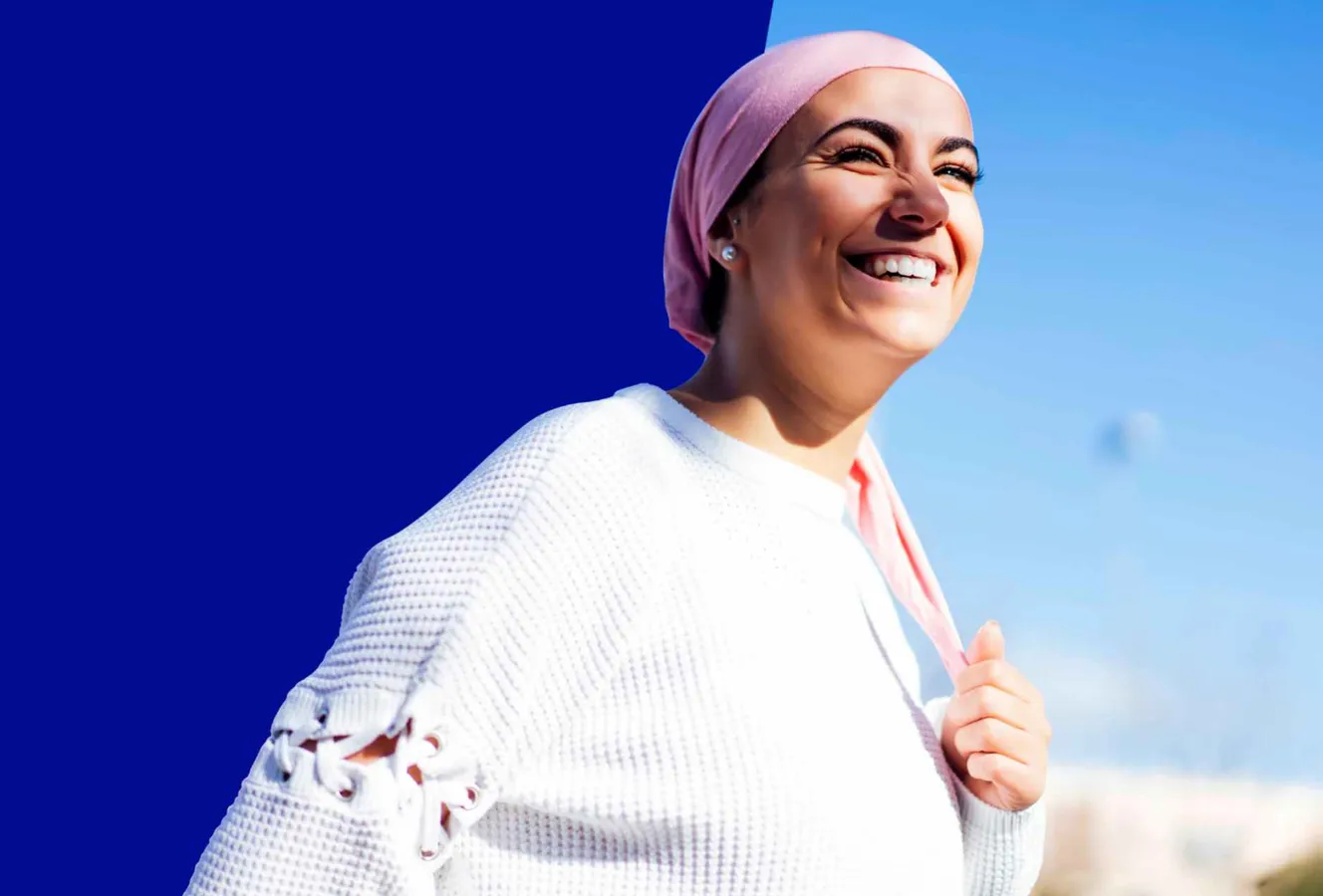 Frau mit Brustkrebs trägt Kopftuch, weißer Pullover, blauer Hintergrund