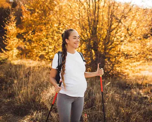 Schwangere Frau mit Krampfadern macht Nordic Walking, Wandern, Natur