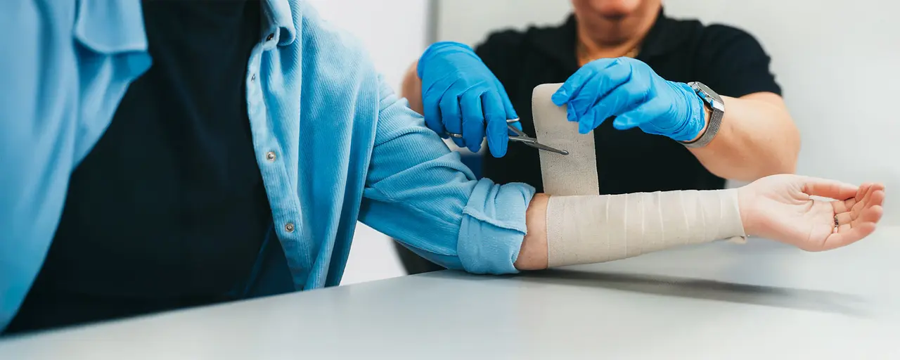 Mann mit Wundheilungsstörung, Wunde wird versorgt von Arzt mit Verband