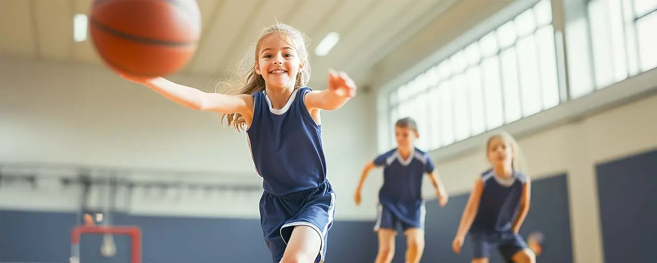 Kind mit Hüftdysplasie, spielt Basketball mit anderen Kindern, läuft hinter Ball her