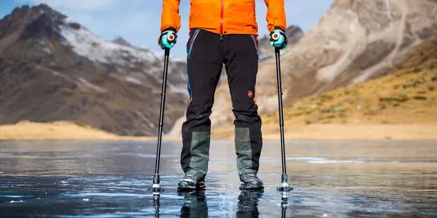Mann in Outdoor-Klamotten steht vor einer Berglandschaft mit zwei Gehstöcken mit SAFETYFOOT-Gummikapsel von Patrick Mayer