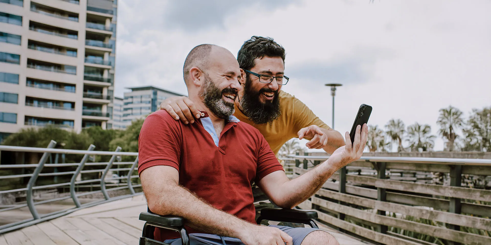 Joviva Zwei Männer Schaün Auf Handy Rollstuhl Buchen Termin Im Sanitätshaus 1920x960