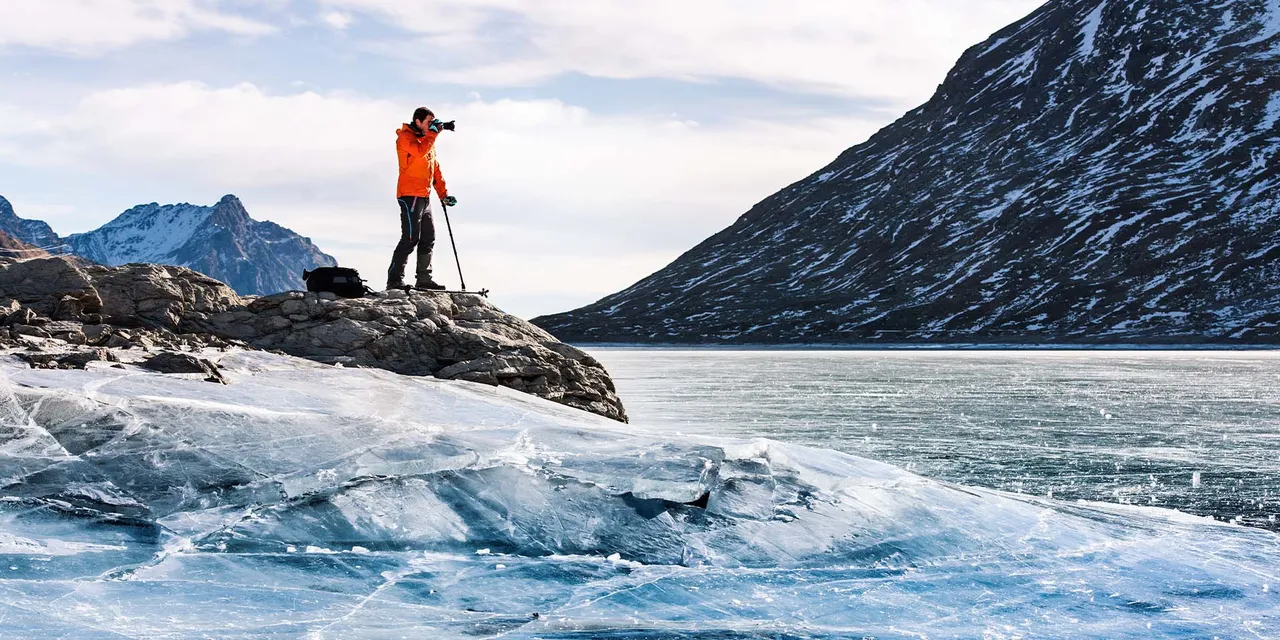 Mann in Outdoor-Klamotten fotografiert einen Gletscher mit zwei Gehstöcken mit SAFETYFOOT-Gummikapsel von Patrick Mayer
