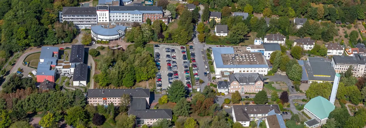 Vogelperspektive auf das Gelände von Volmar Vital in Wetter mit mehreren Gebäuden, Parkplatz und umgebenden Grünflächen.