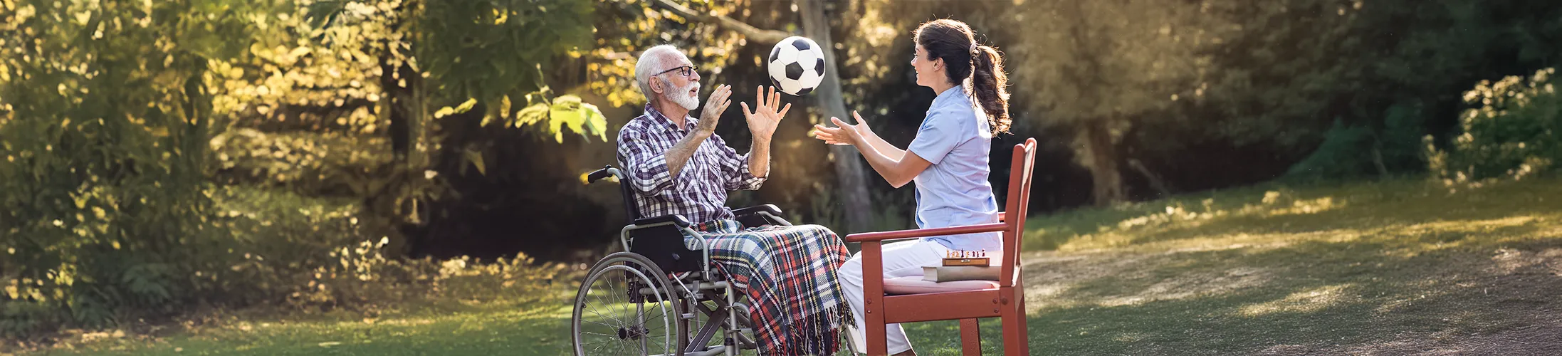 Huntington-Krankheit, Mann im Rollstuhl mit Therapeutin und Ball, Krankengymnastik gegen Bewegungsstörungen