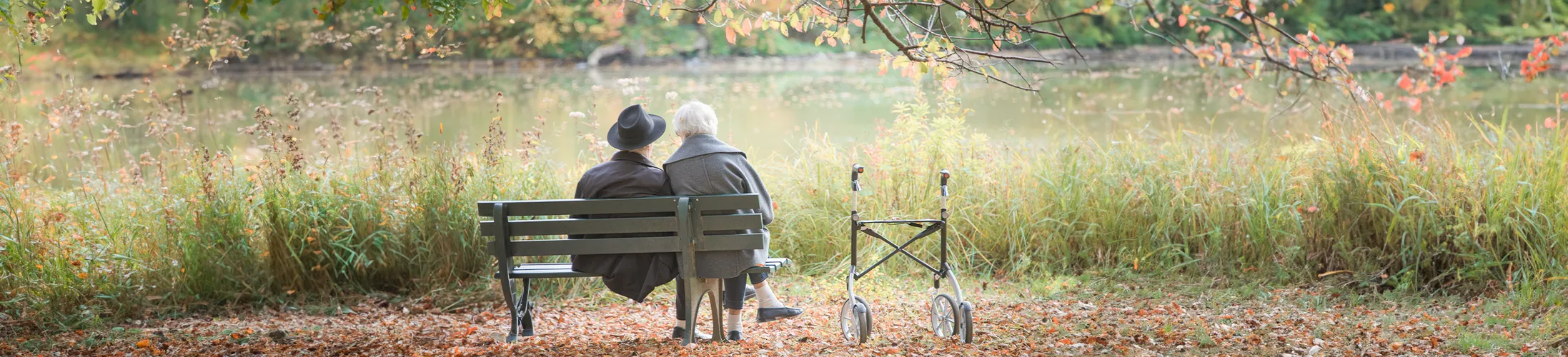 Muskelschwäche, Gangunsicherheit, älteres Paar mit Rollator sitzt auf Bank in Park, Kraftlosigkeit