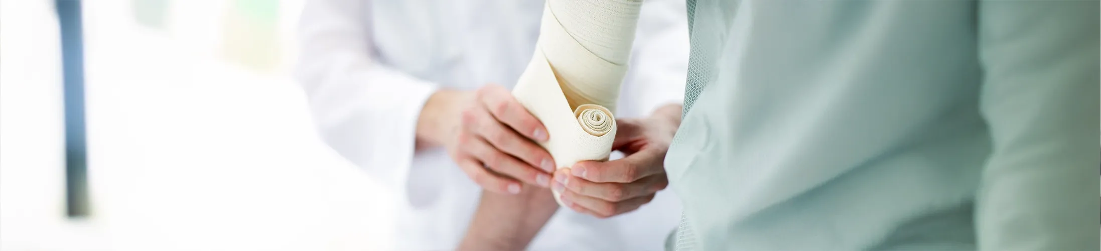 Mann mit Wunde bekommt Arm von Arzt verbunden, Kompression, grünes Oberteil