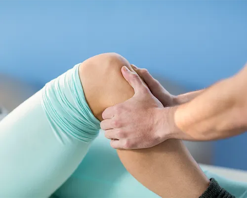 Patella-Schmerzen, Therapeut fasst Frau an Wade, Schmerzen vorderer Teil des Knies, Tape, Ruhigstellung
