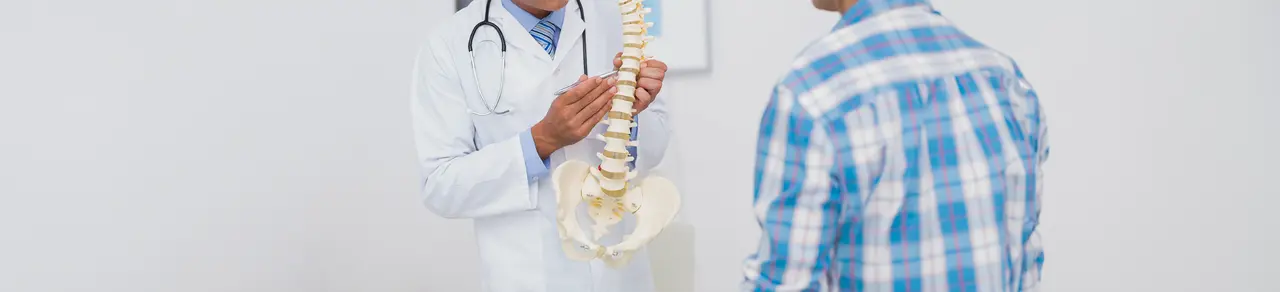Arzt zeigt Patient mit Kaudasyndrom Modell von Wirbelsäule