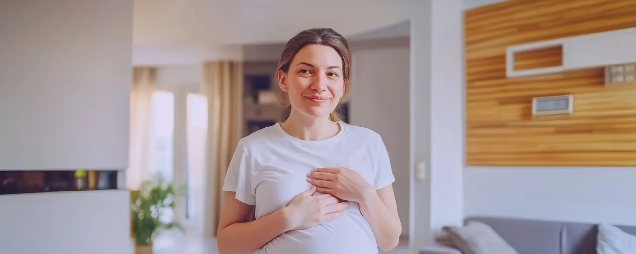 Schwangere Frau hält sich die Brust wegen Brustschmerzen, trägt weißes T-Shirt, Wohnung mit Sofia und Wandregal im Hintergrund