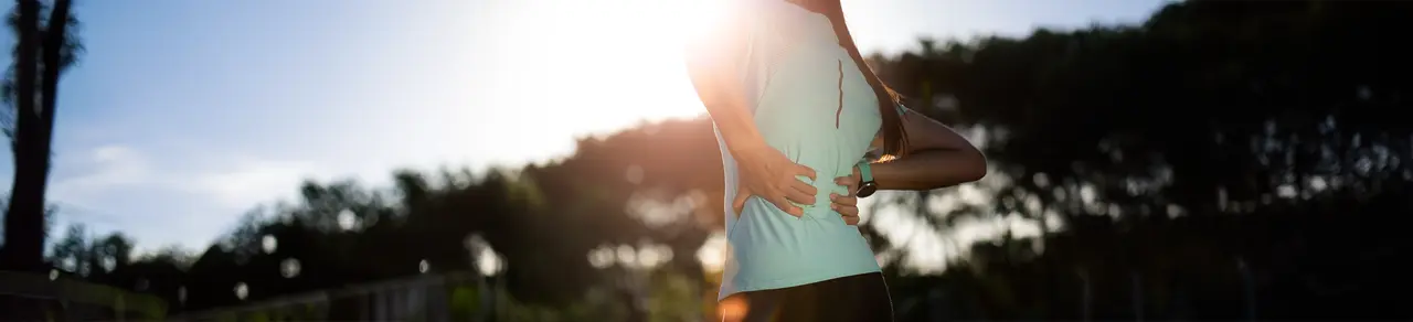 Spinalkanalstenose, Joggerin greift sich mit beiden Händen an den unteren Rücken