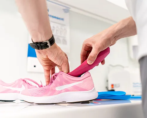 Fußschmerzen, Fachkraft in Sanitätshaus misst Sneaker aus, orthopädische Einlagen