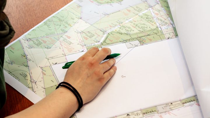 Hand mit grünem Stift an einem Gartenplan