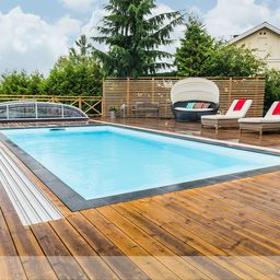 Moderner Außenpool mit kristallklarem Wasser und hölzernem Deck, umgeben von bequemen Sonnenliegen und einem stilvollen Sichtschutz aus Holz.