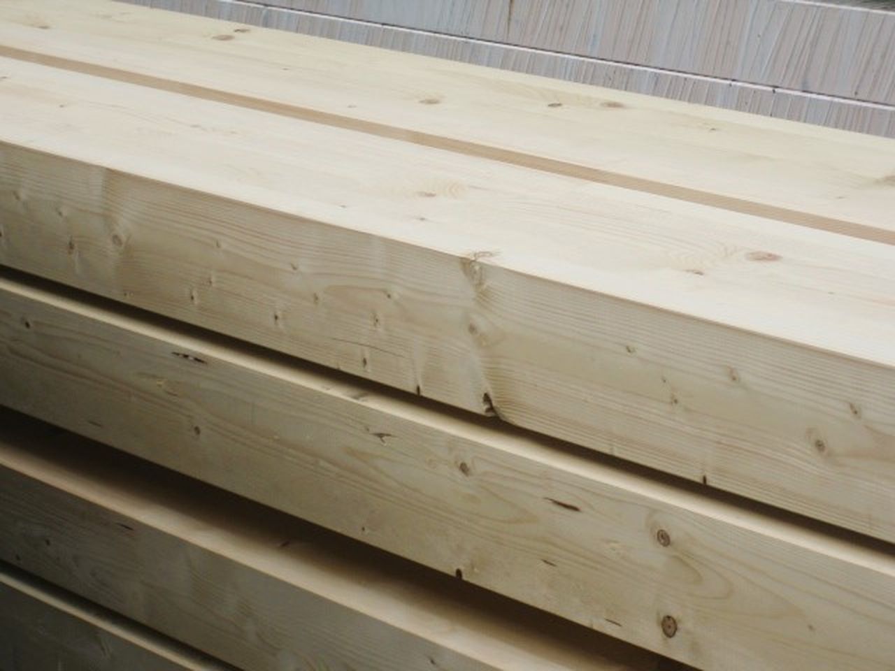 Mehrere KVH Holzbalken aus Fichte liegen auf einem Stapel zusammen und werden aufgrund ihrer hohen Formstabilität häufig für tragende Bauzwecke verwendet.