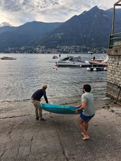 Due persone sollevano lo scafo per portarlo in acqua