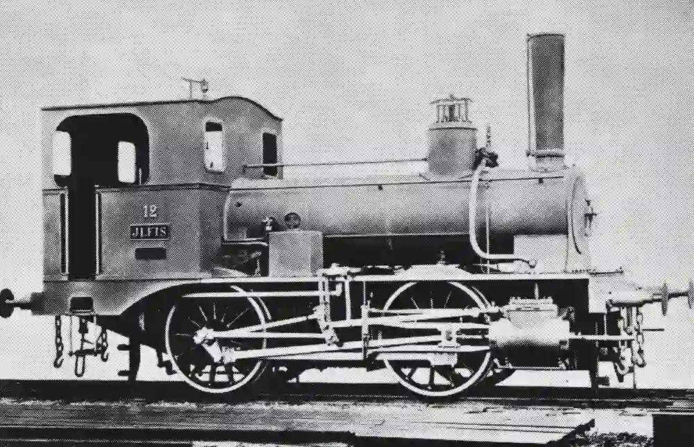 L'immagine mostra una locomotiva a vapore storica. In particolare, si tratta della locomotiva n. 12 "Ilfis" delle Ferrovie dello Stato di Berna (BEB). Questa compagnia ferroviaria era attiva in Svizzera nel XIX secolo.