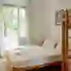 L'immagine mostra un'invitante e luminosa camera dell'Hotel Marthahaus con un letto matrimoniale e un letto a castello, ampie finestre e vista sul verde. L'immagine irradia pace e comfort.