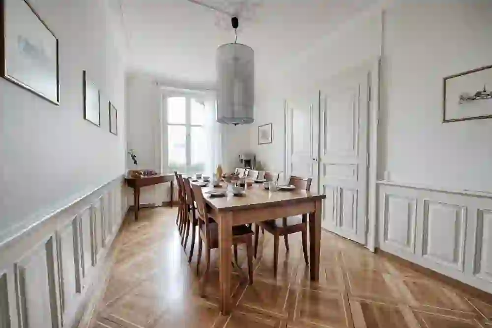 The picture shows an elegant dining room in the B&B by the pavilion with a large wooden table and covered seating. The bright, airy interior design invites you to enjoy cosy meals together.
