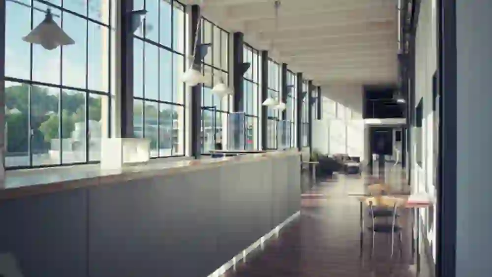 Le couloir avec ses grandes fenêtres et son charme industriel dégage une impression de calme. La lumière naturelle et l'intérieur moderne créent une atmosphère détendue et stylée.